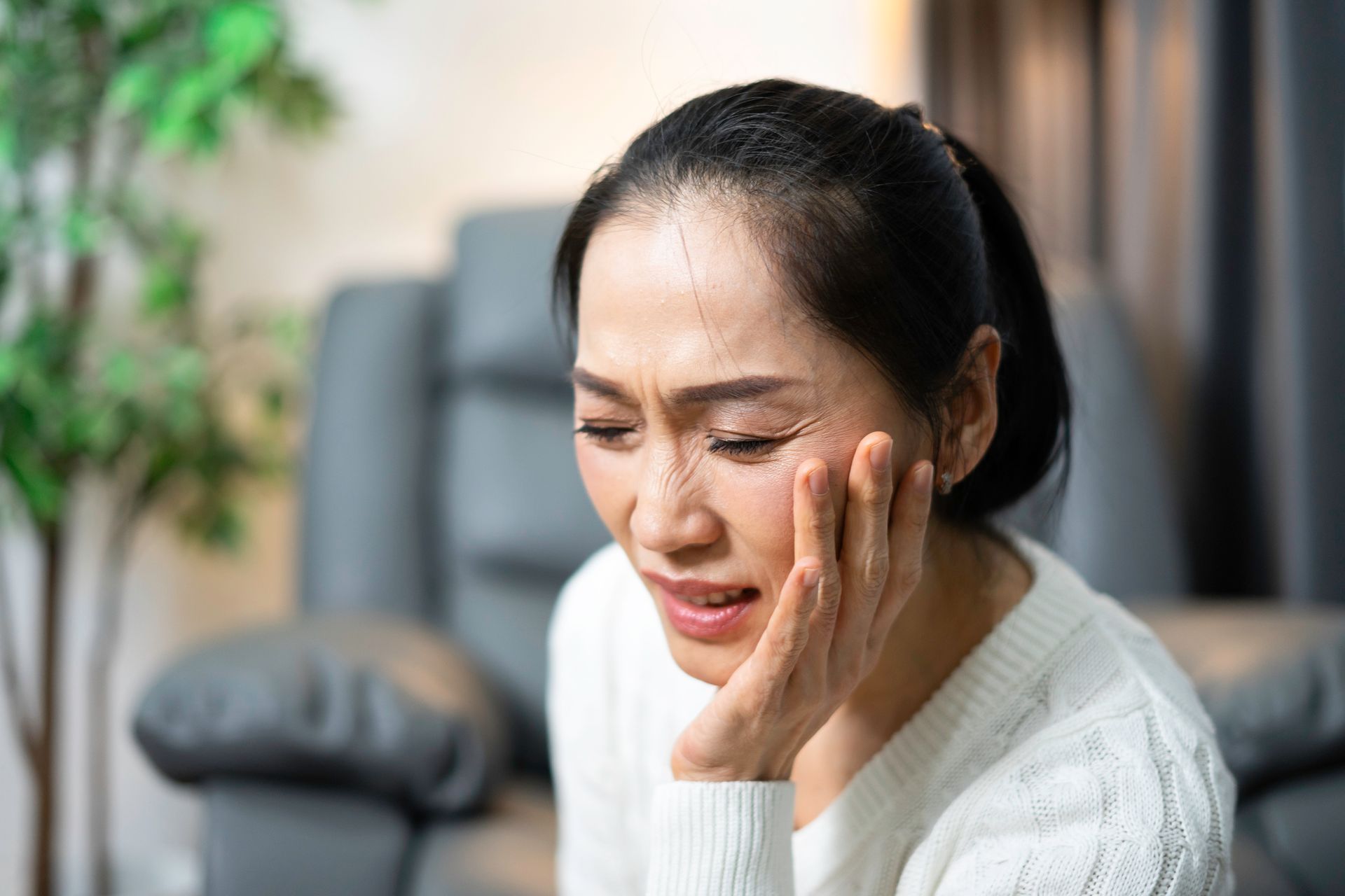 A woman is touching her face in pain due to a toothache.