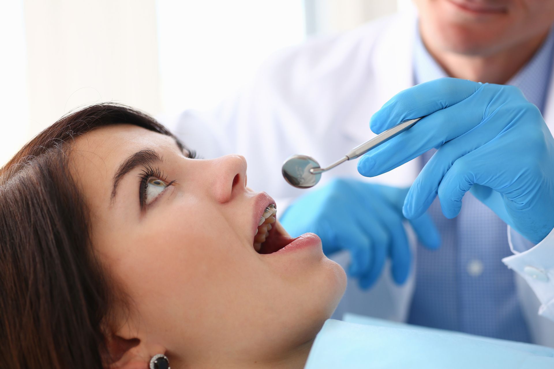 A woman at Henderson Family Dentistry in Henderson, NC, is examining her teeth due to tooth pain wit