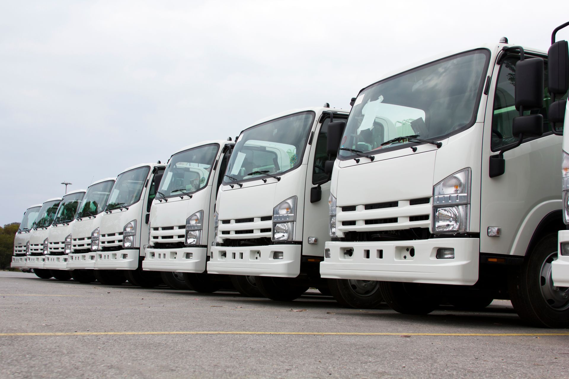 White delivery trucks parked in a row on a gray day.