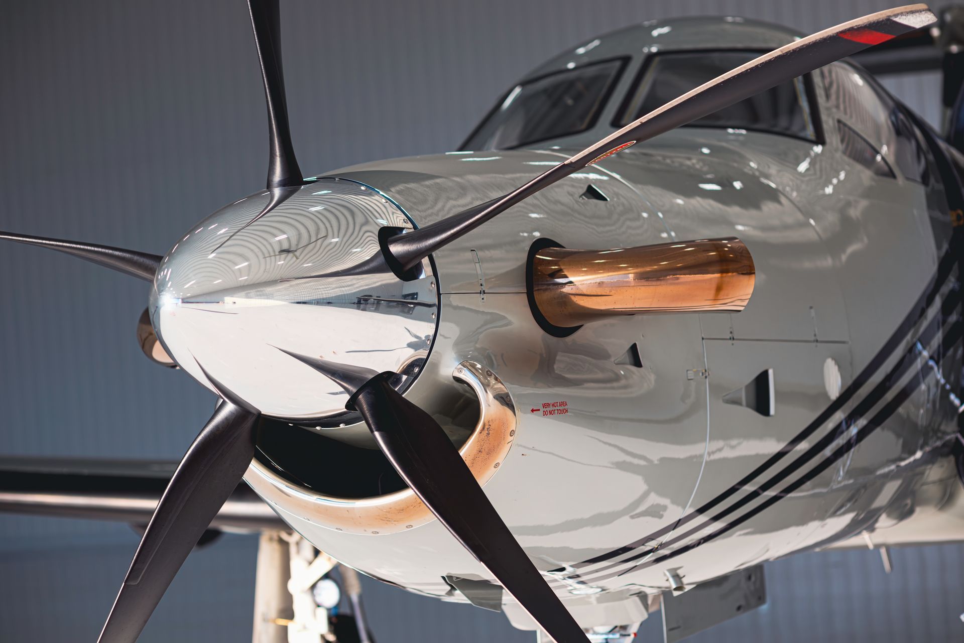 Close-up of a silver airplane nose with a spinning propeller, displaying a copper-colored air intake.