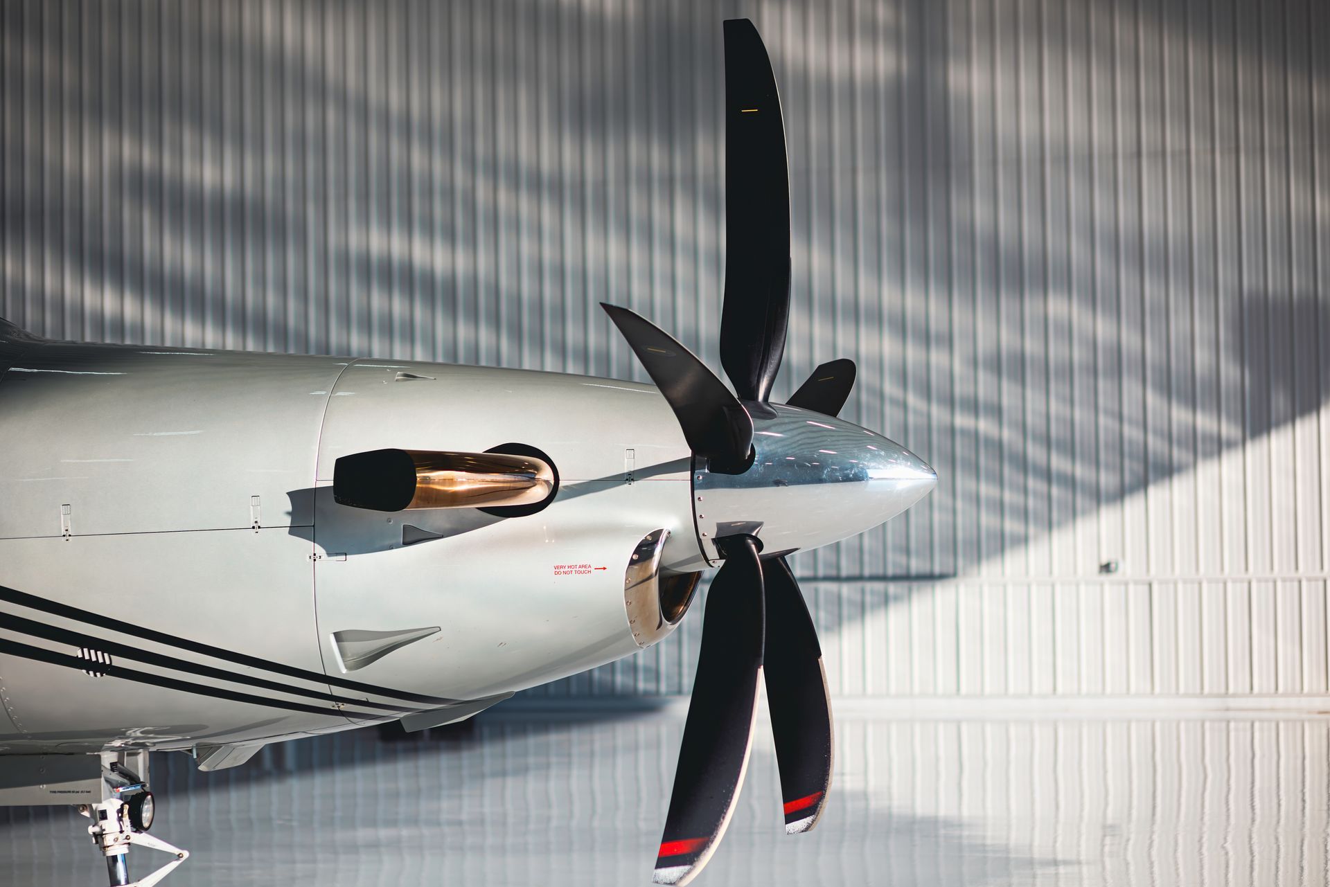Airplane nose with propeller and engine, in a hangar.