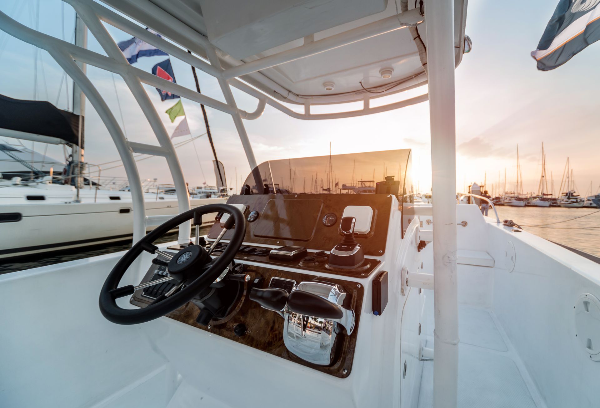 Inside of a white boat's steering console; steering wheel, gauges, and windshield visible.