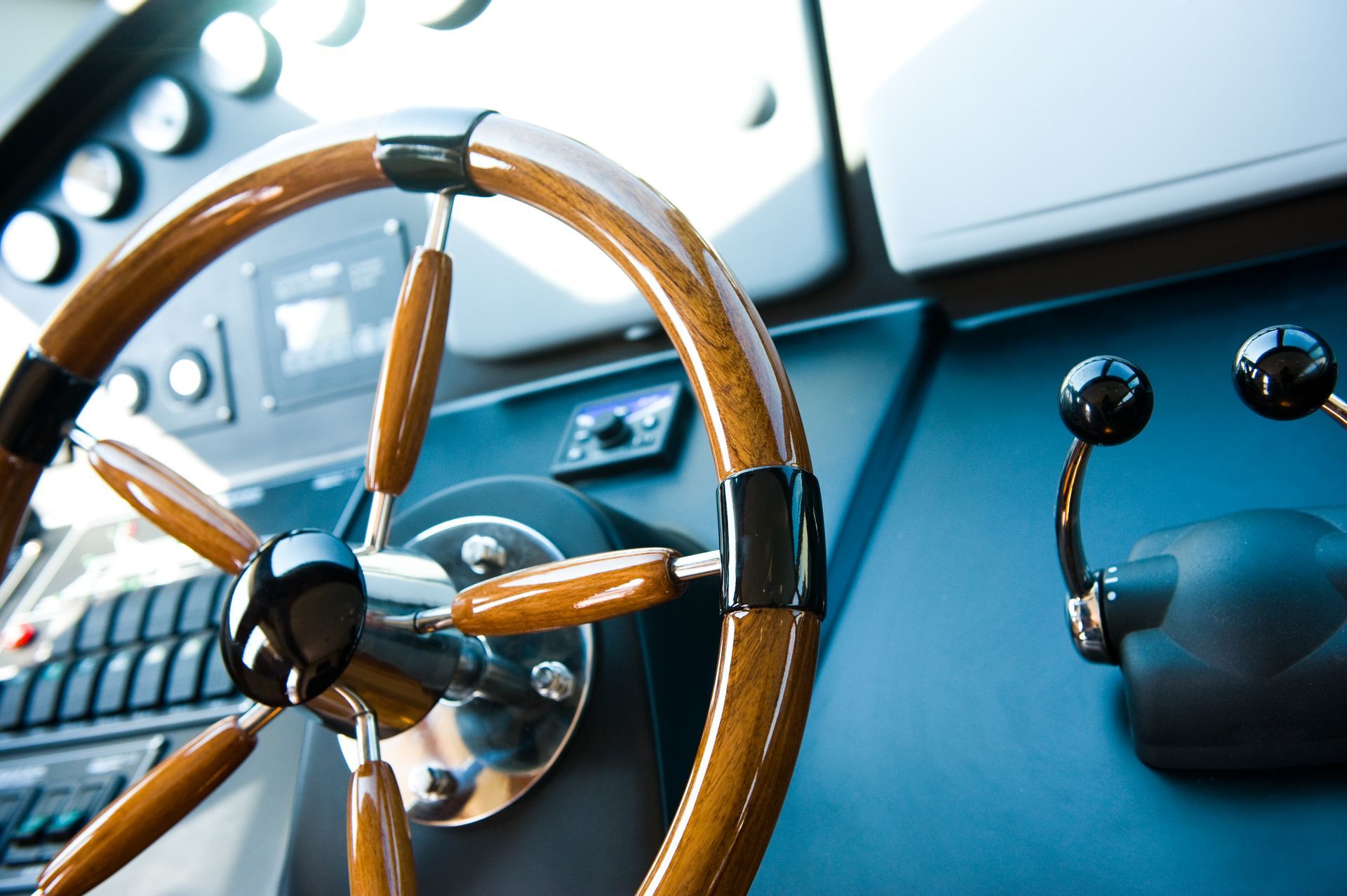 Wooden ship's wheel with controls on a dashboard.