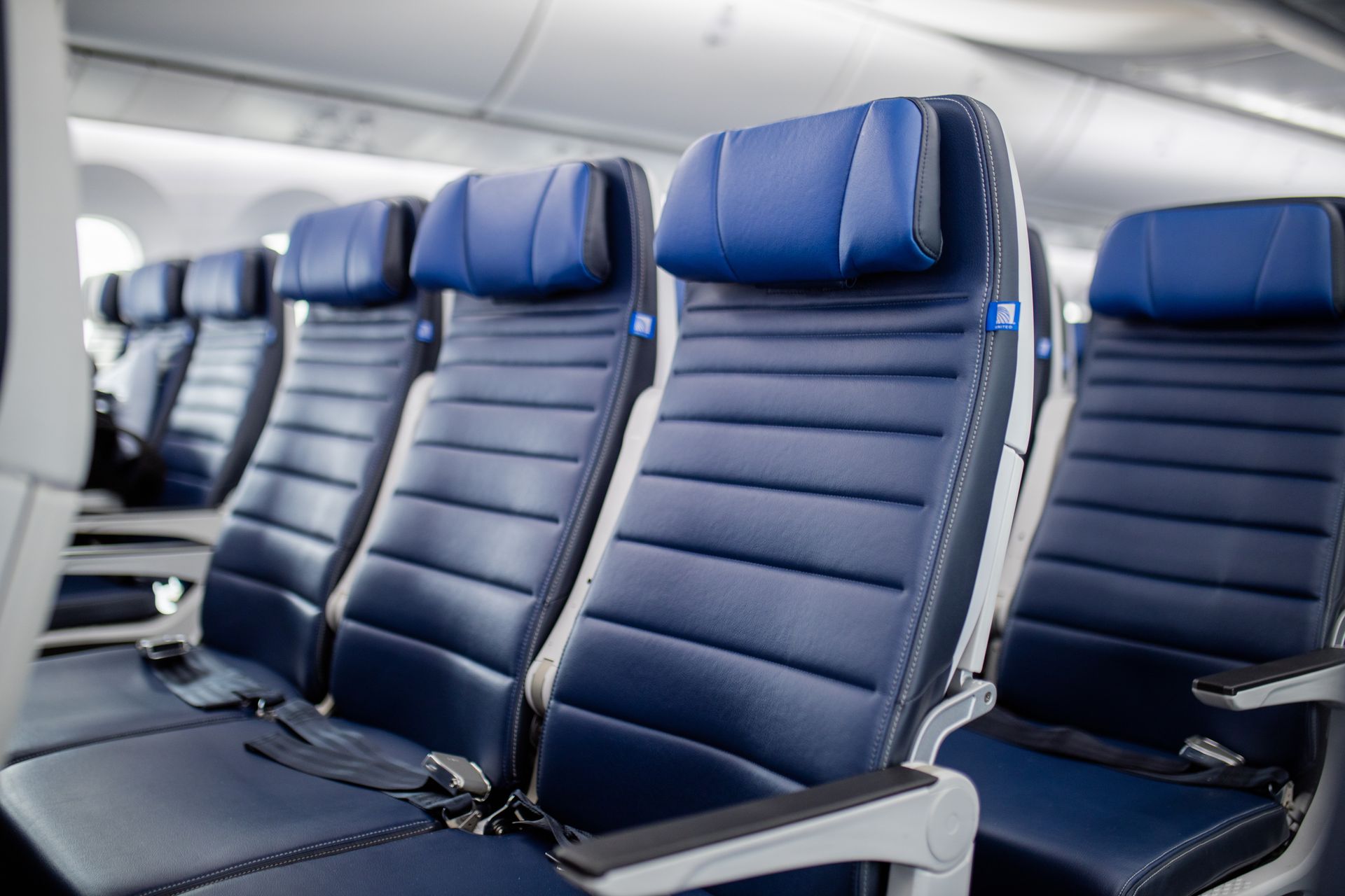 Blue airplane seats in a row, seen from a side angle, inside a plane.