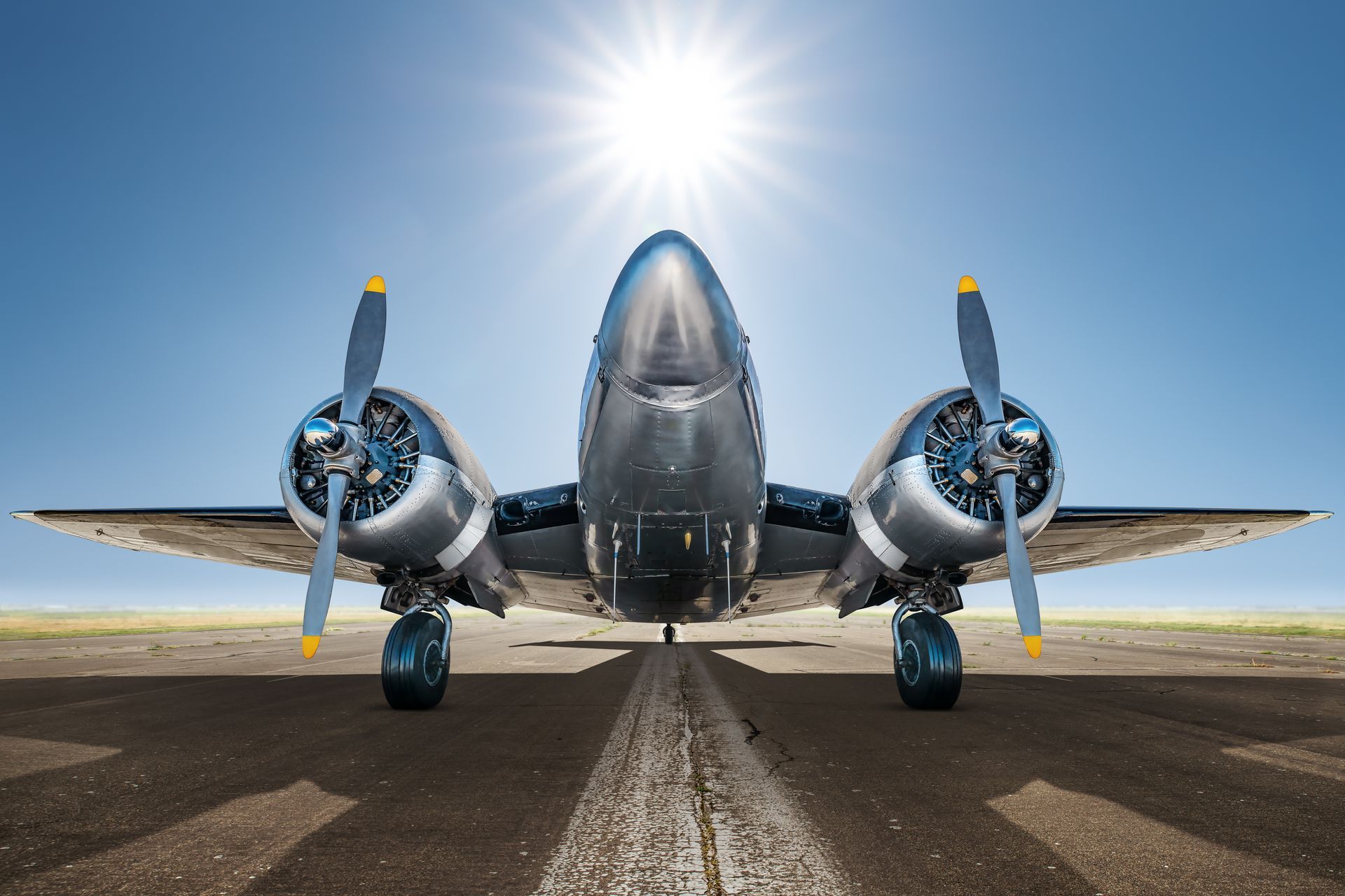 Airplane on a runway with sun shining overhead.