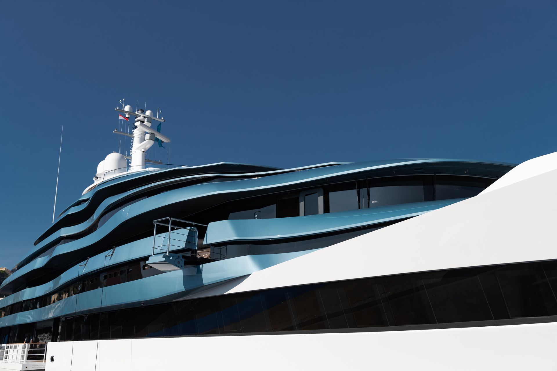 Blue and white luxury yacht against a clear blue sky.