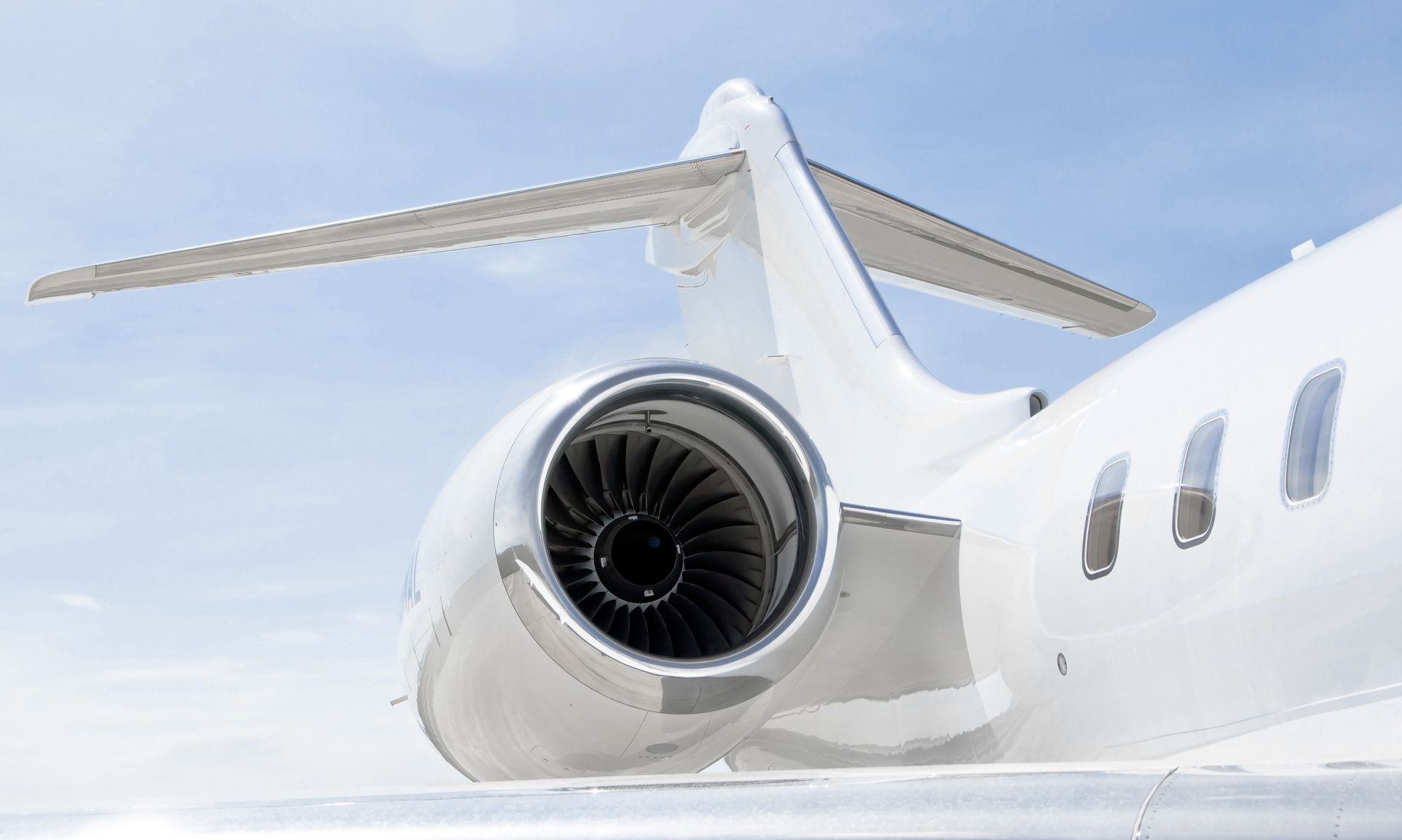 Close-up of a jet engine on a parked airplane, in a hangar, metallic gray, with a central white sphere.