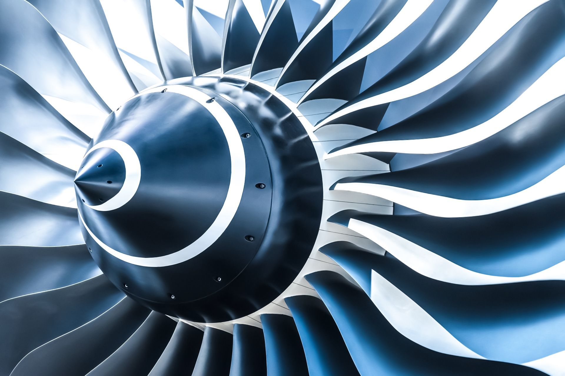 Close-up of a jet engine with metallic blue fan blades and a cone-shaped hub.