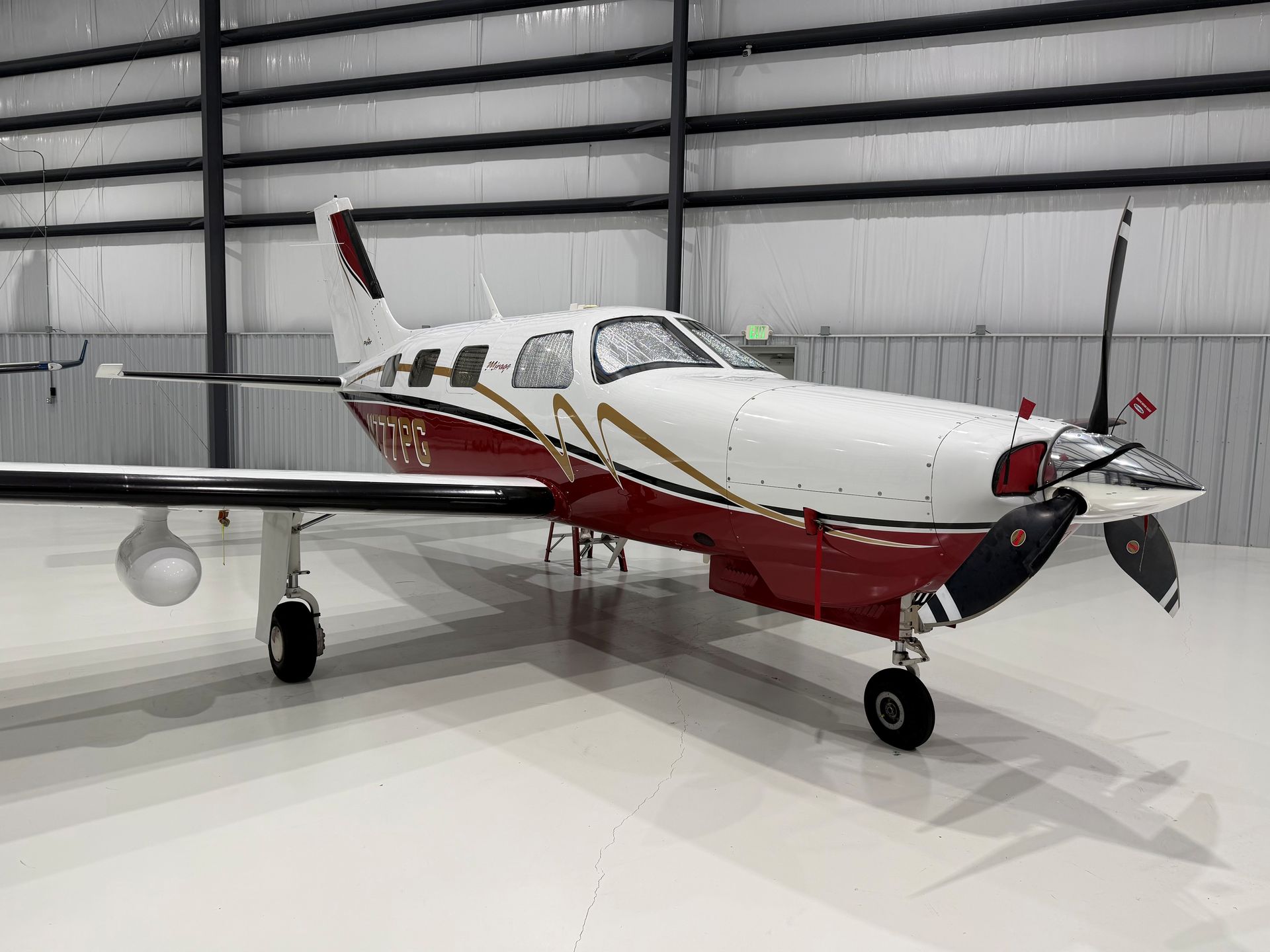 Airplane propeller, shiny metal blades, close-up, orange and white fuselage.
