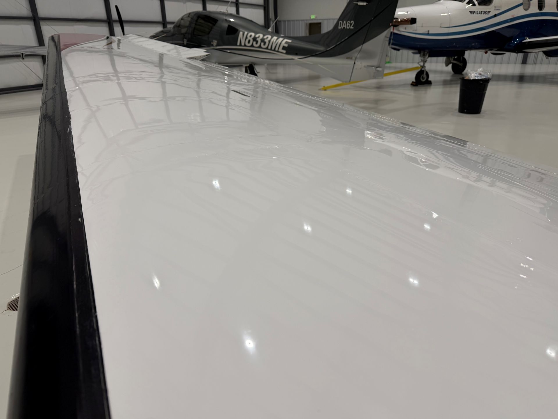 Airplane inside a maintenance hangar, with yellow access stairs and tow bar, on a concrete floor.