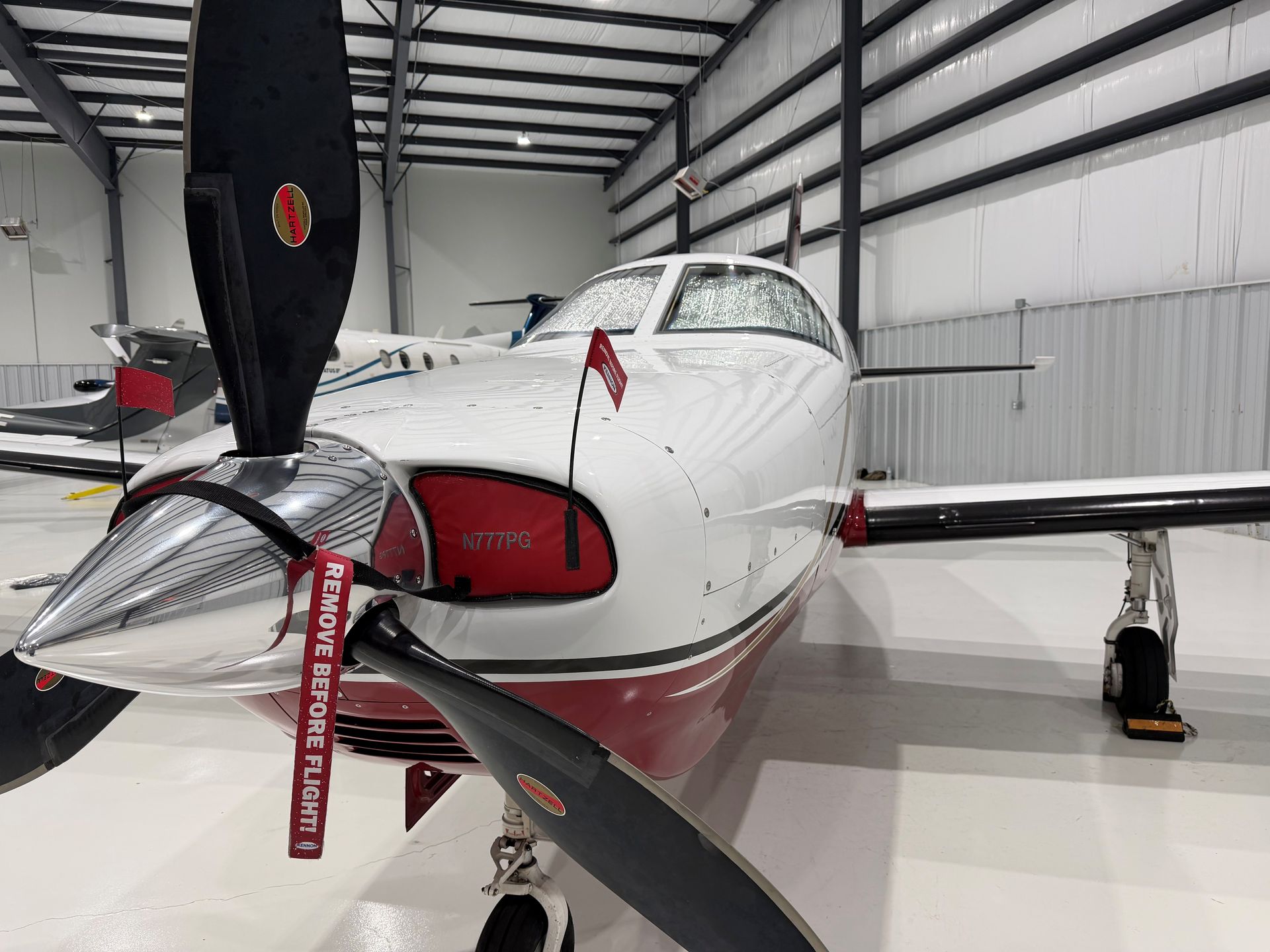Airplane inside a maintenance hangar, with yellow access stairs and tow bar, on a concrete floor.