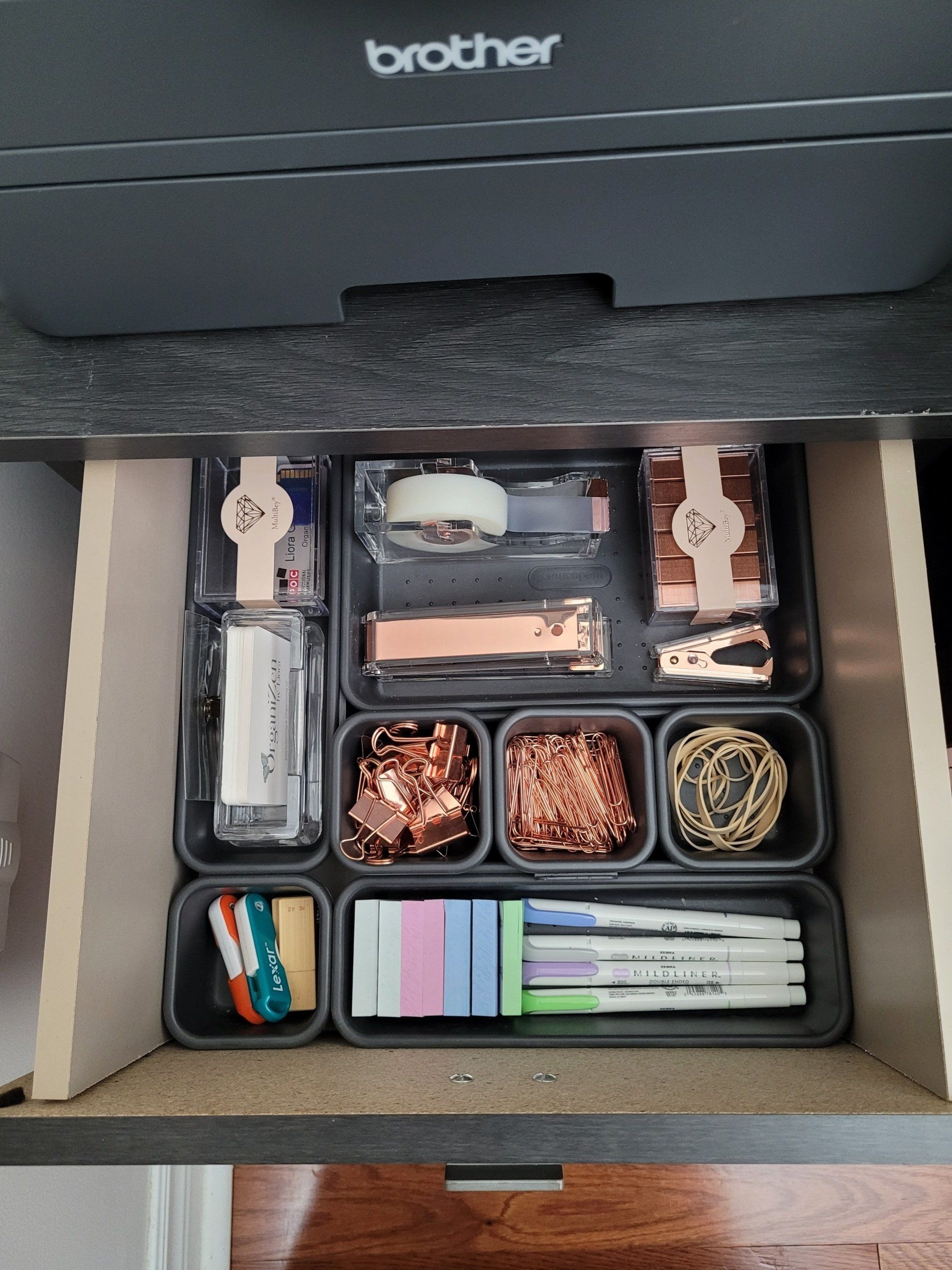 A drawer filled with office supplies and a printer.