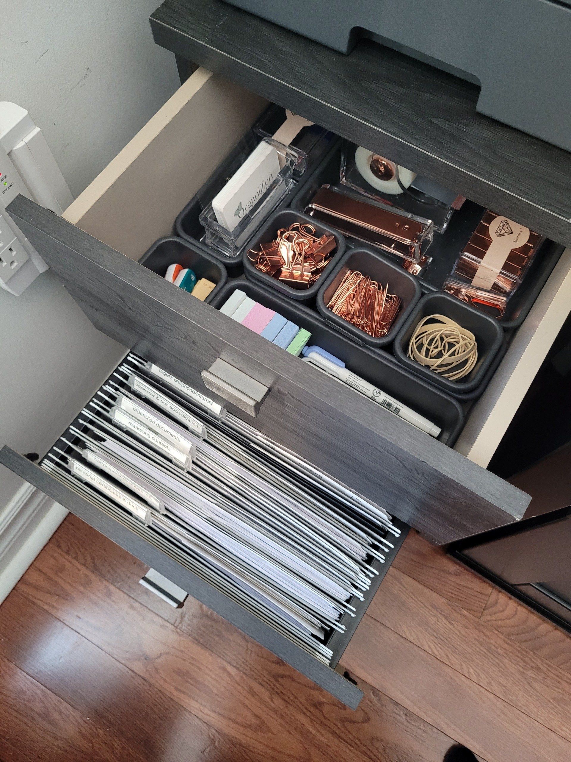 A drawer filled with binders and other office supplies.