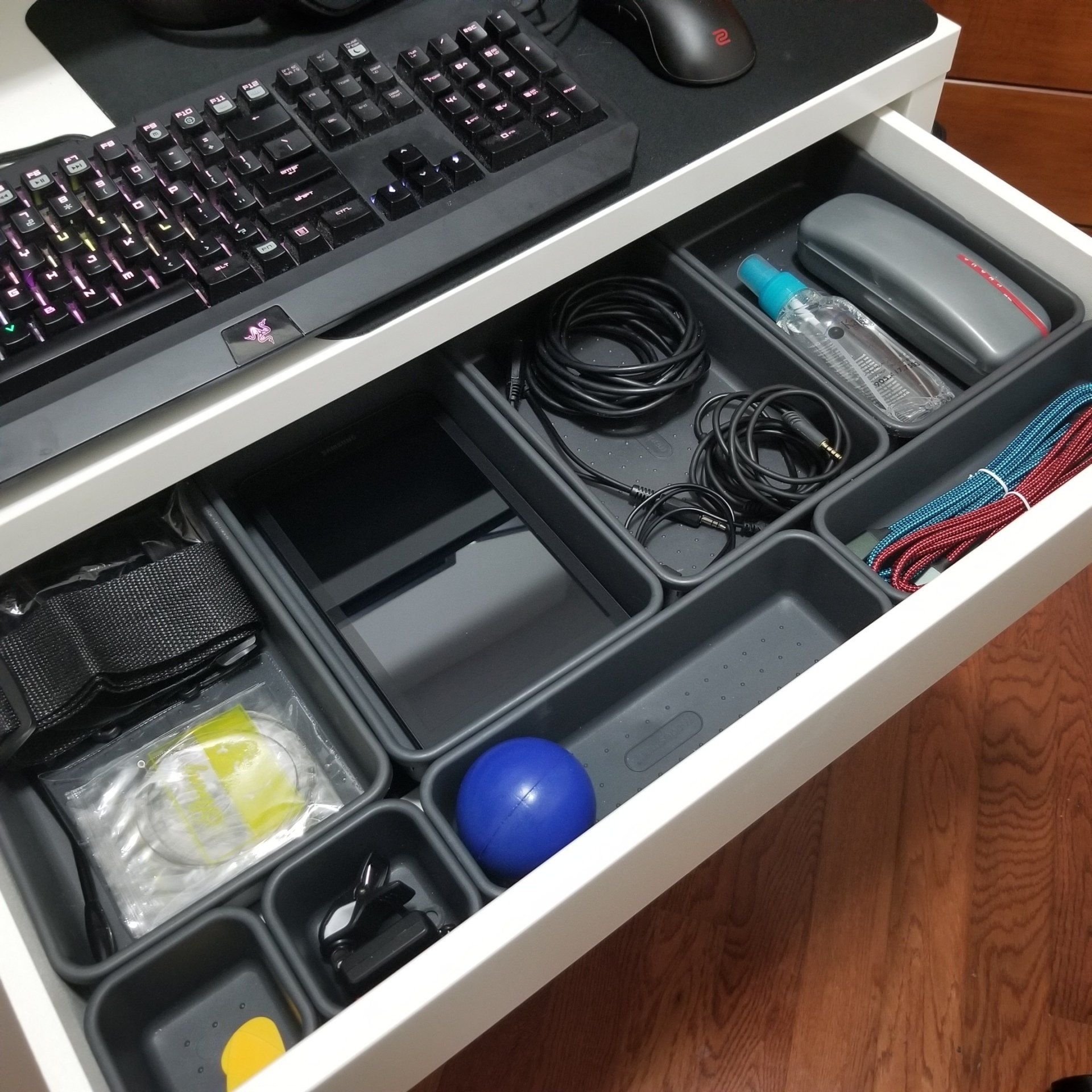 A drawer filled with various items including a keyboard and mouse