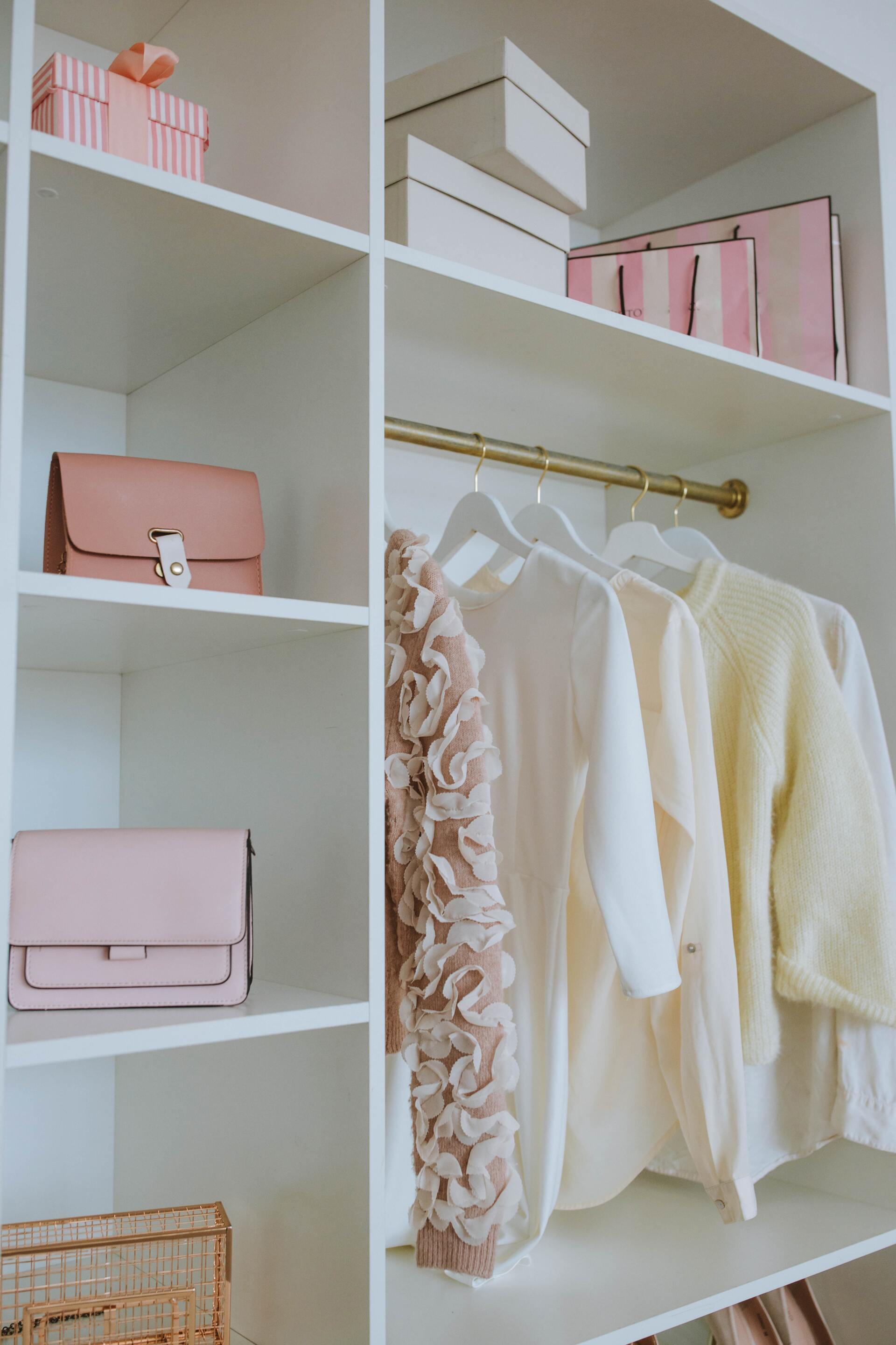 A closet filled with clothes and pink boxes.