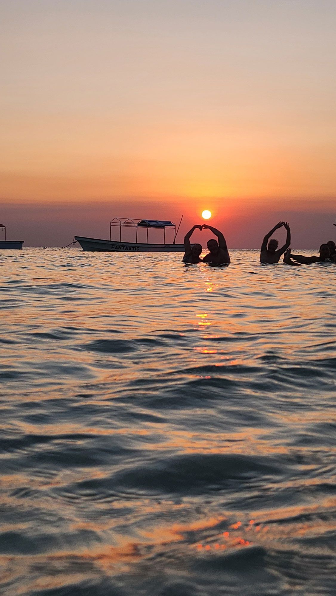 un gruppo di persone sta nuotando nell'oceano al tramonto