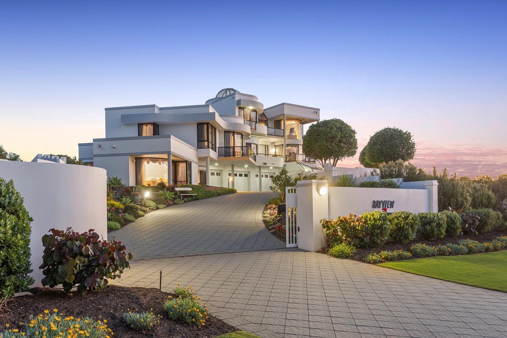 Modern white mansion with a long driveway at dusk. Modern white mansion with a long driveway at dusk.
