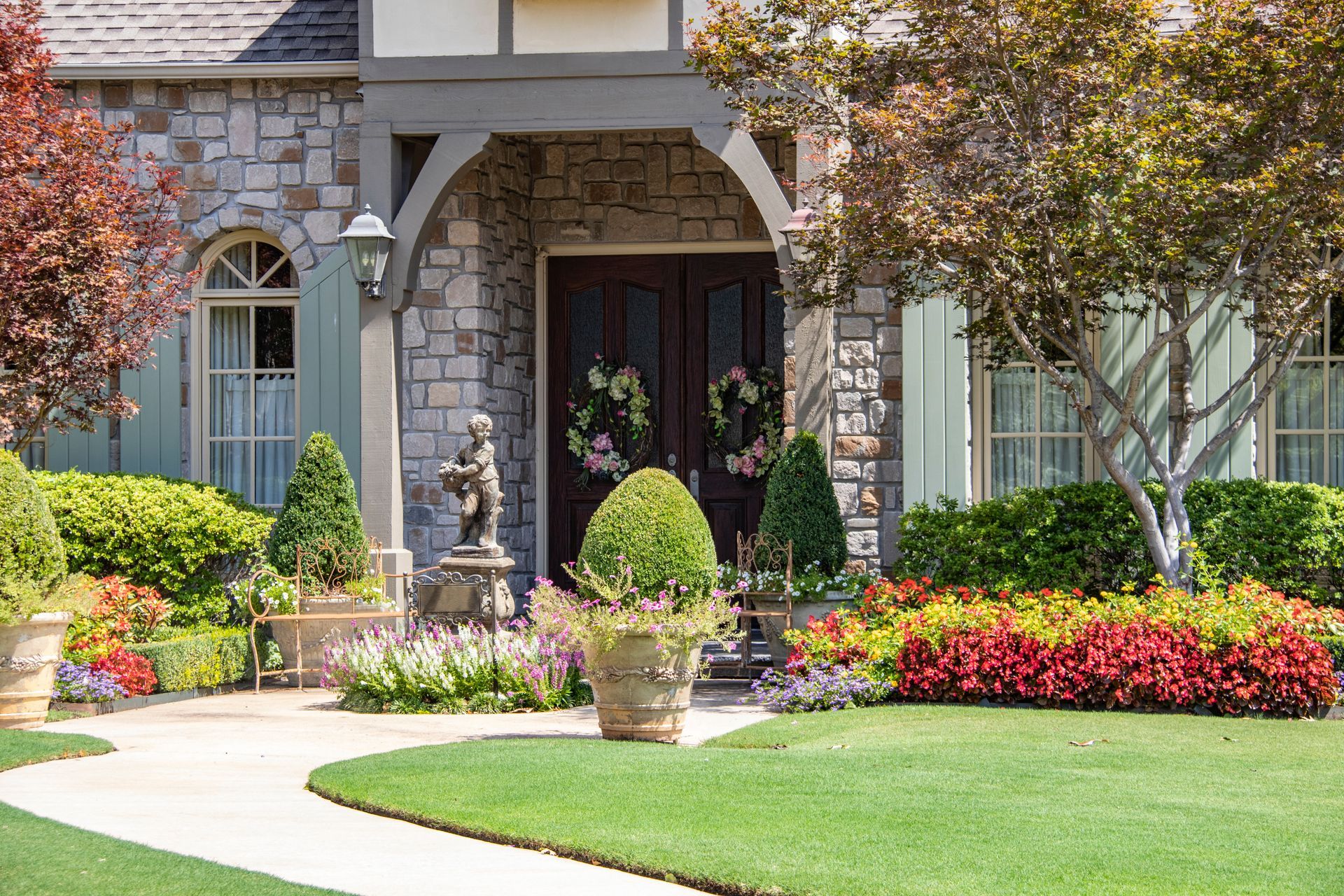 Stone house with manicured landscaping and curved walkway.