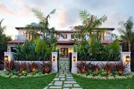 Luxurious two-story home with lush landscaping, palm trees, and stone pathway leading to the entrance.