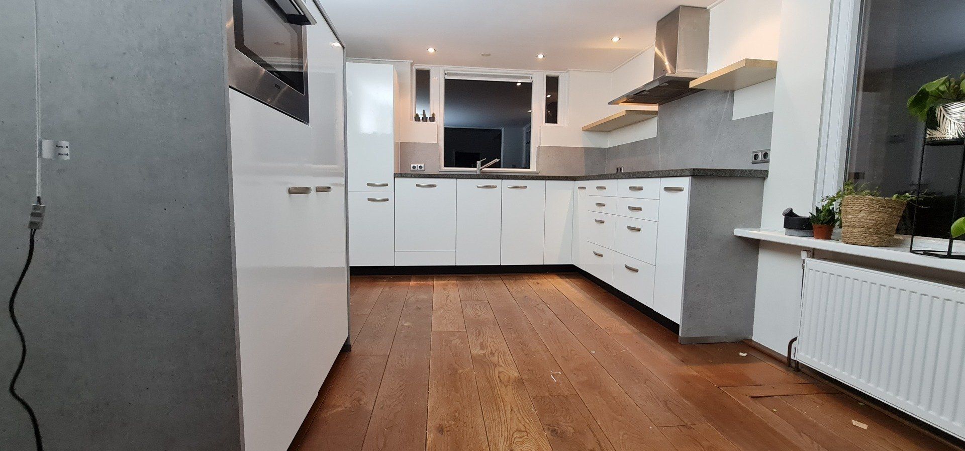 Een keuken met witte kasten en een houten vloer