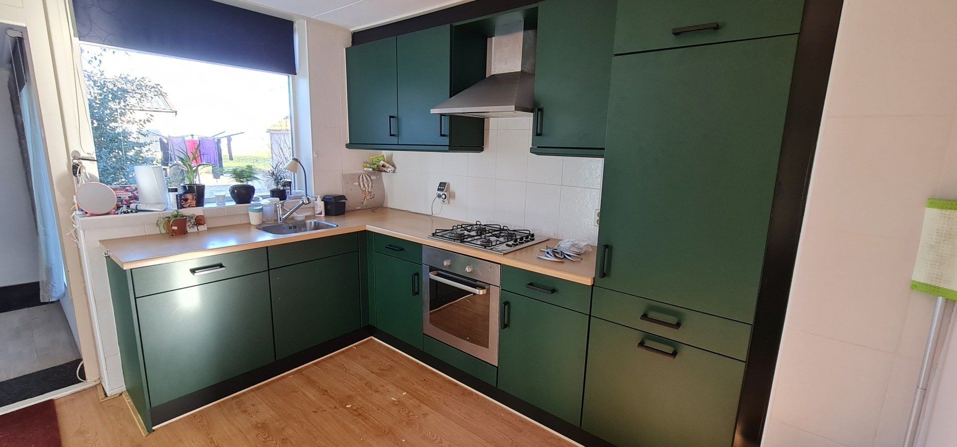 Een keuken met groene kasten en een kookplaat oven