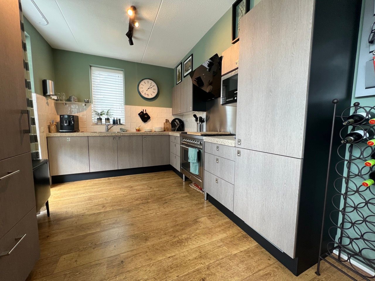 Een keuken met een klok aan de muur en een wijnrek.