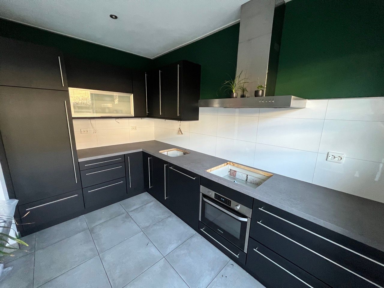 Een keuken met zwarte kasten en witte aanrechtbladen