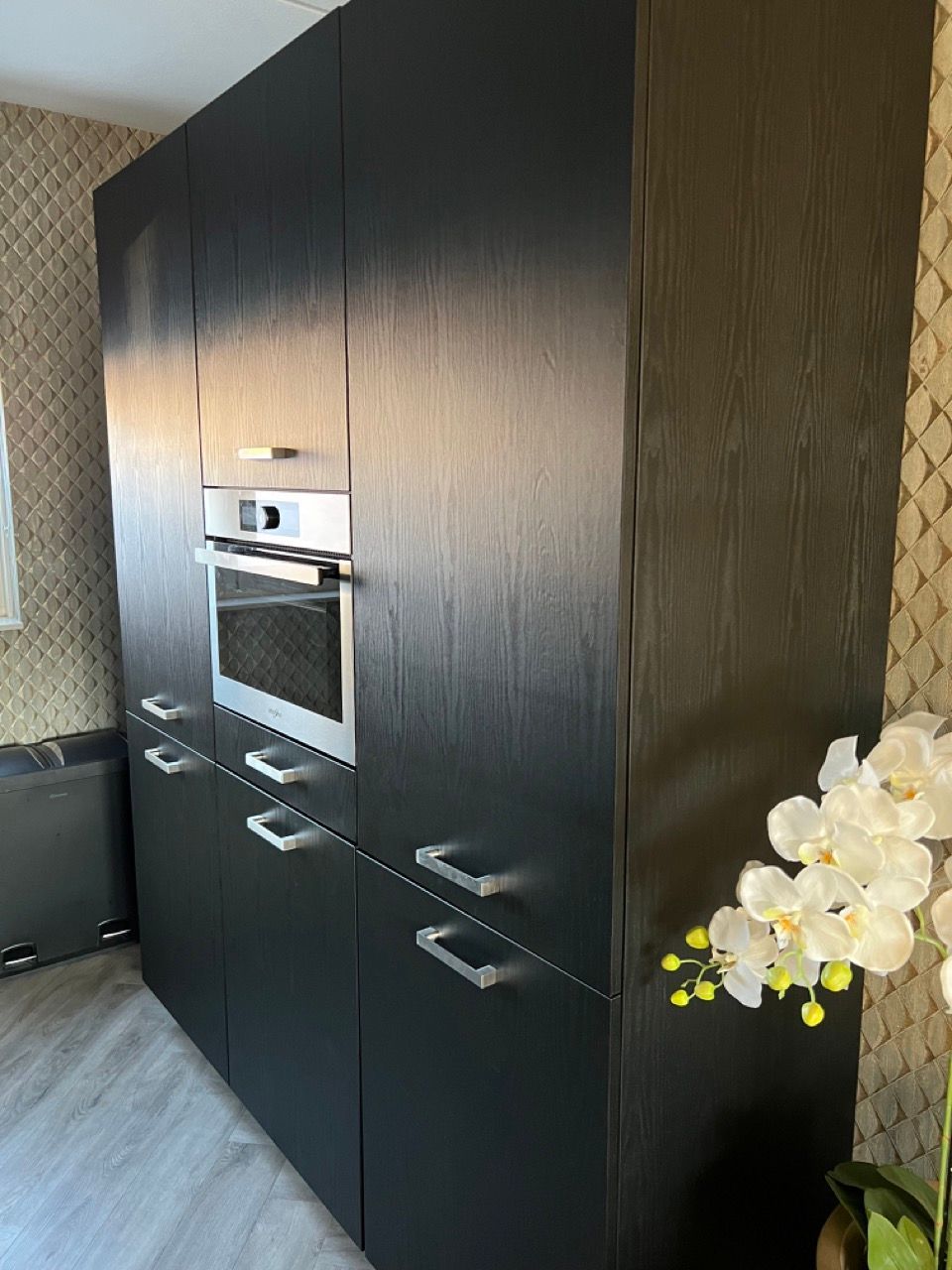 Een keuken met zwarte kasten en een roestvrijstalen oven.