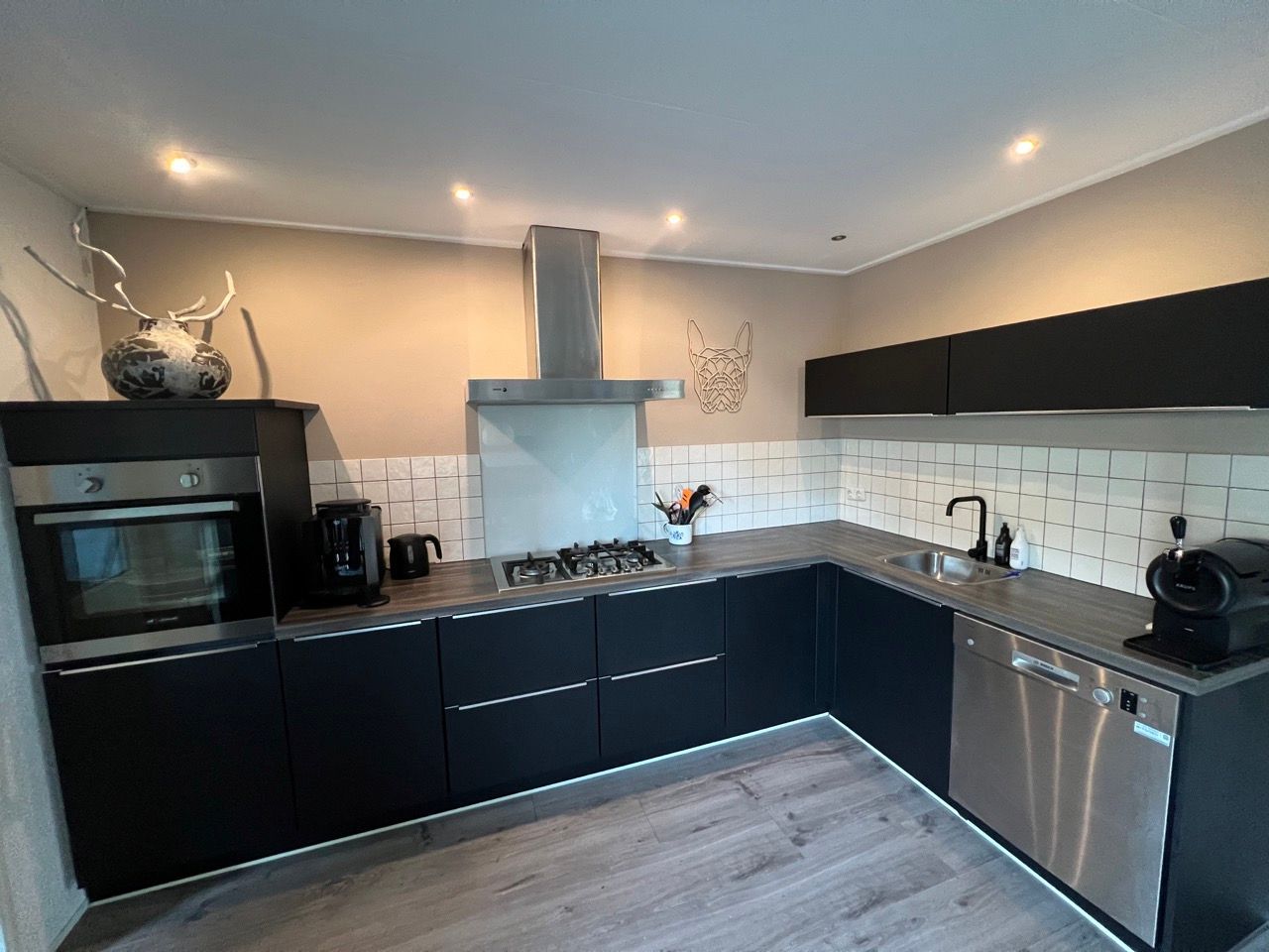 Een keuken met zwarte kasten en roestvrijstalen apparatuur