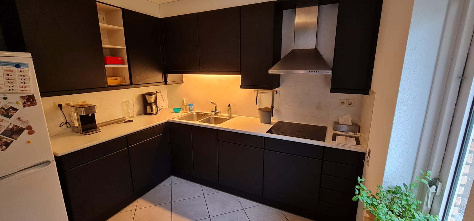 Een keuken met zwarte kasten en een witte koelkast.