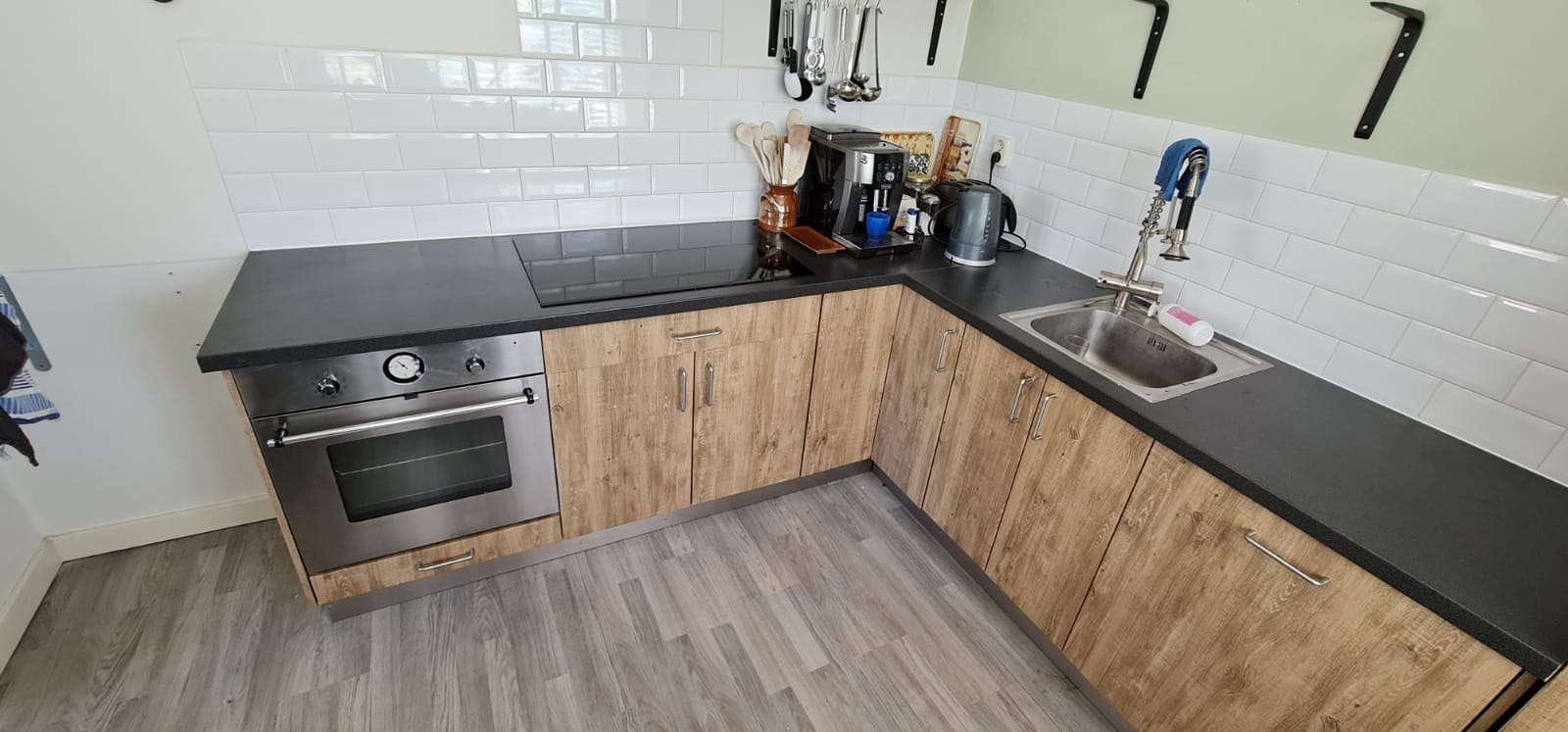 Een keuken met houten kasten, roestvrijstalen apparatuur, een gootsteen en een fornuis.