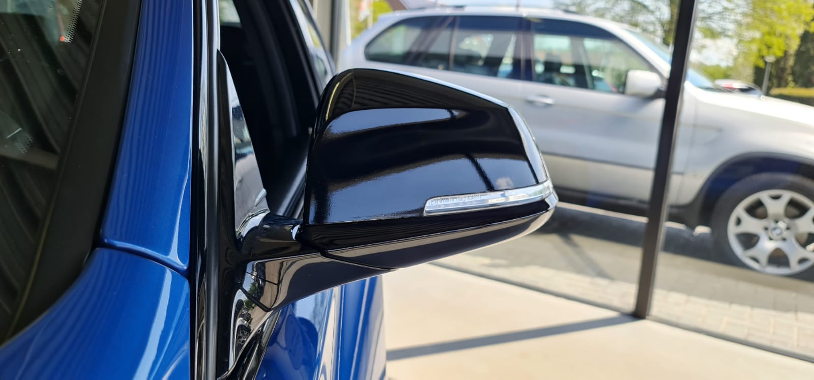 Een blauwe auto staat geparkeerd op een parkeerplaats naast een zilveren auto.