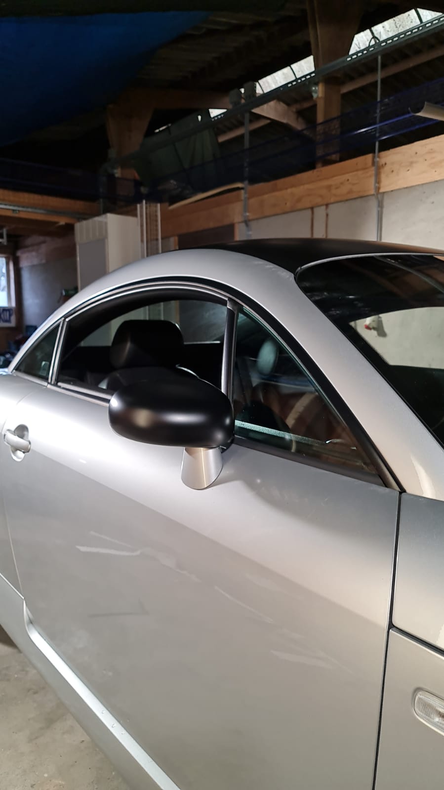 Een zilveren sportwagen staat geparkeerd in een garage.