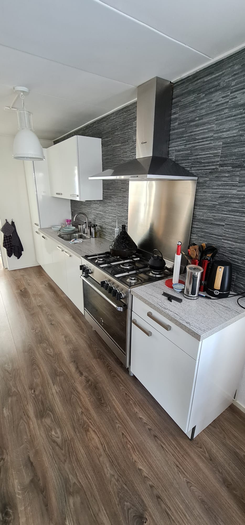 Een keuken met een fornuis, oven, gootsteen en kasten.