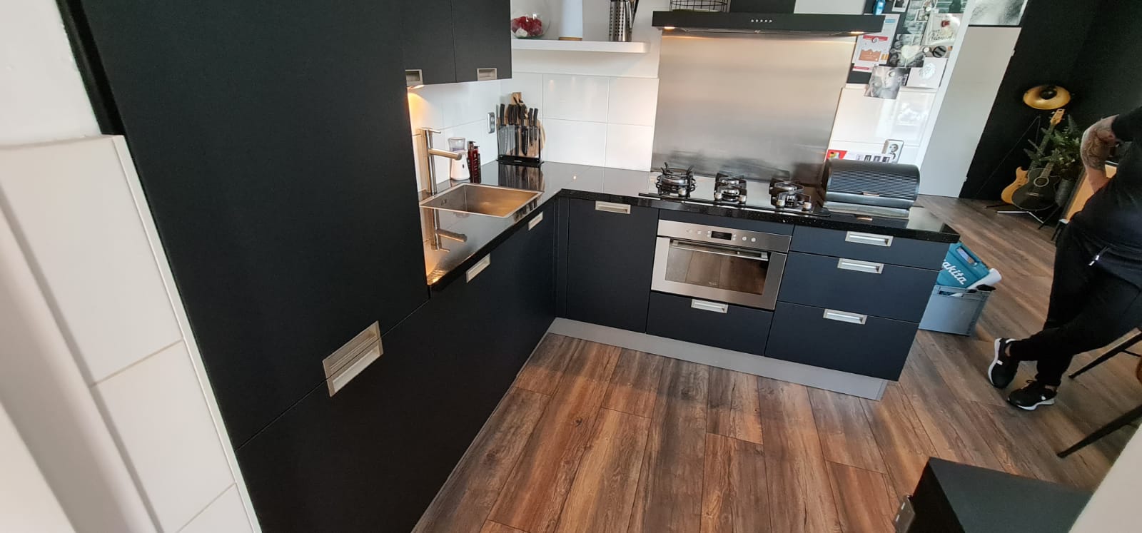 Een keuken met zwarte kasten en houten vloeren