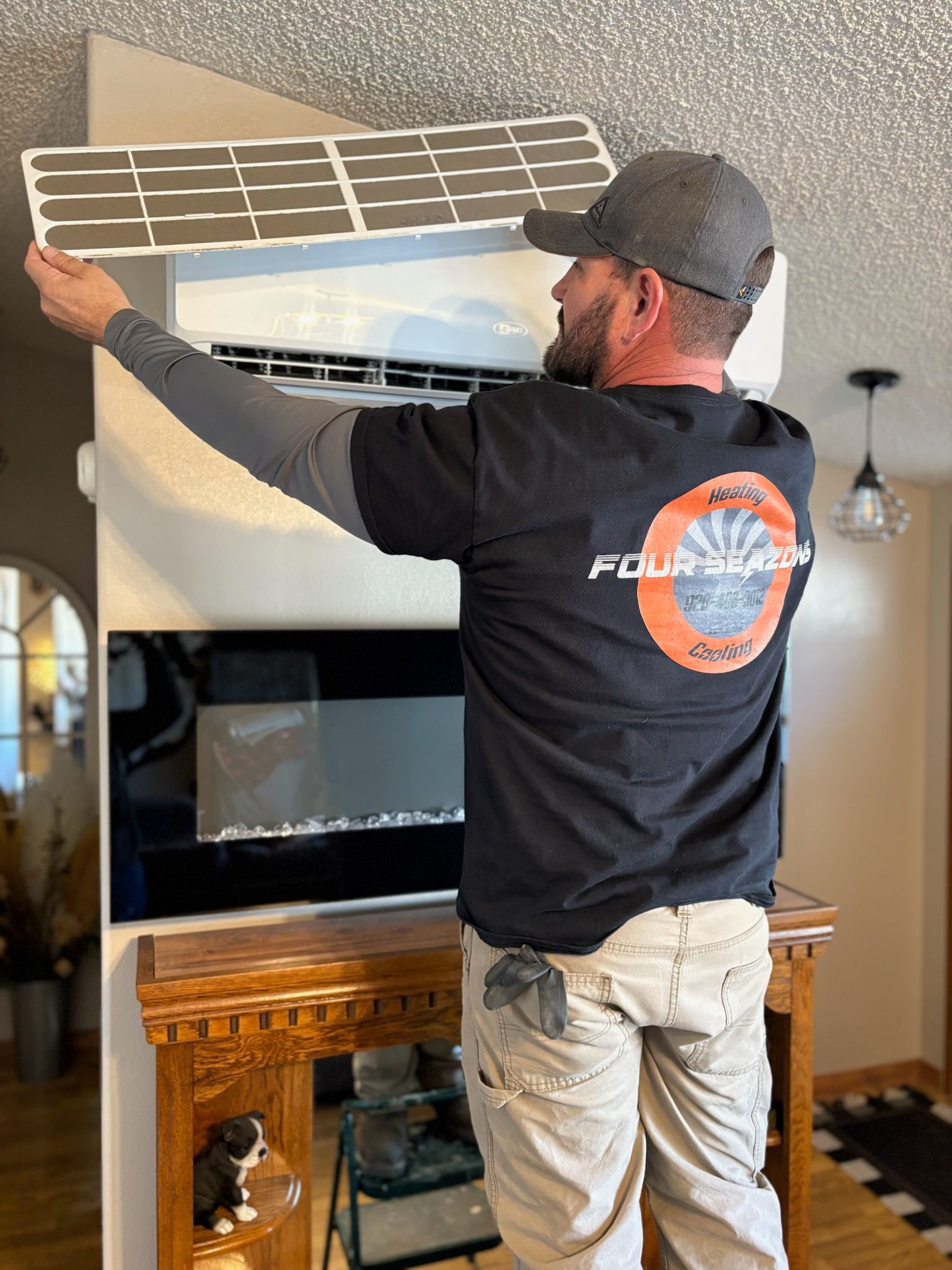 A man wearing a four shades shirt is working on an air conditioner.