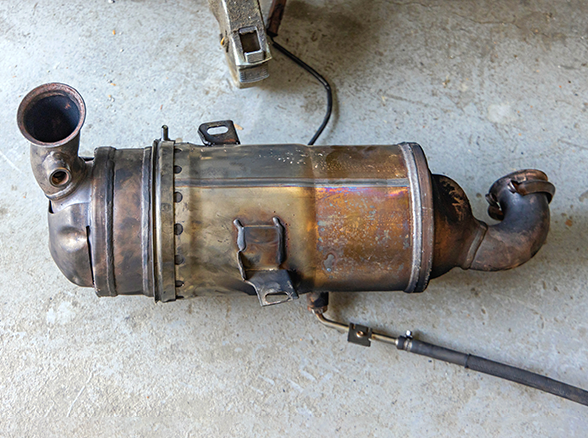 A close up of a rusty diesel particulate filter in a car