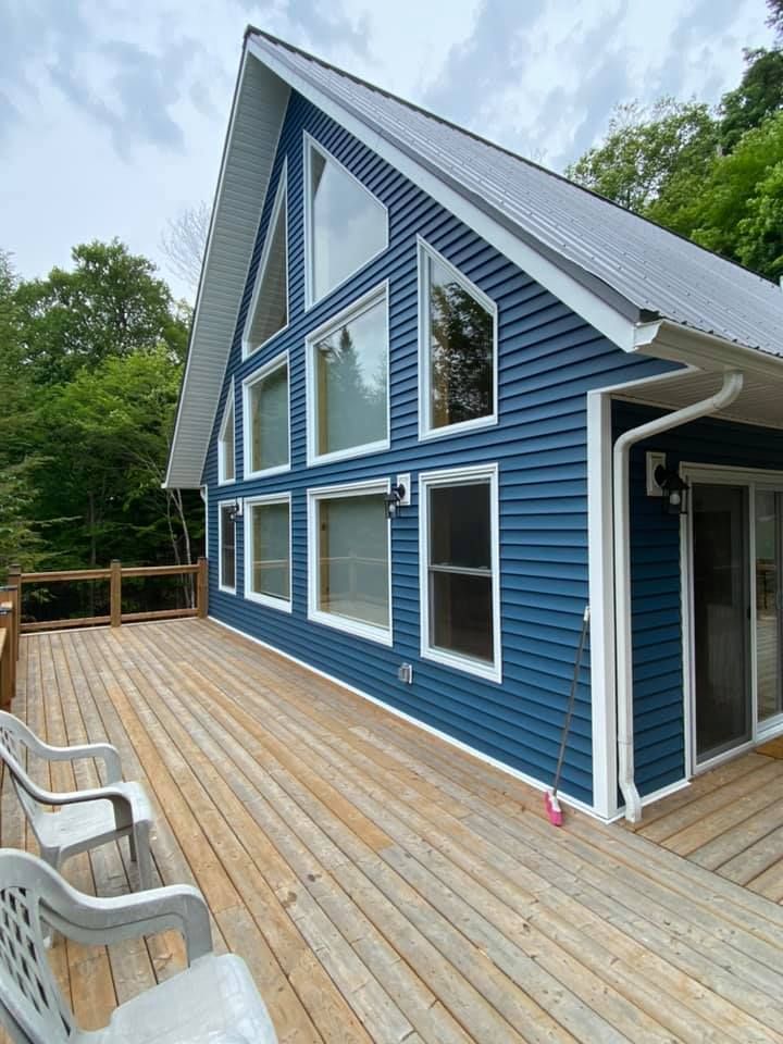 A blue house with a large deck in front of it.