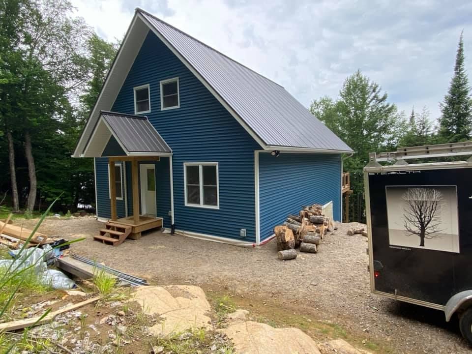 A small blue house with a metal roof is being built.