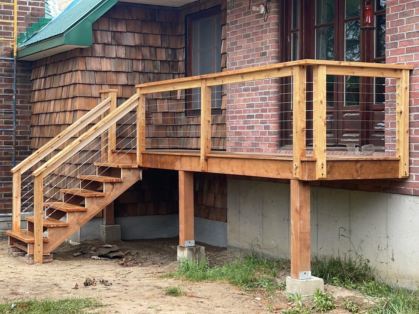 A wooden deck with stairs leading up to the front door of a brick house.