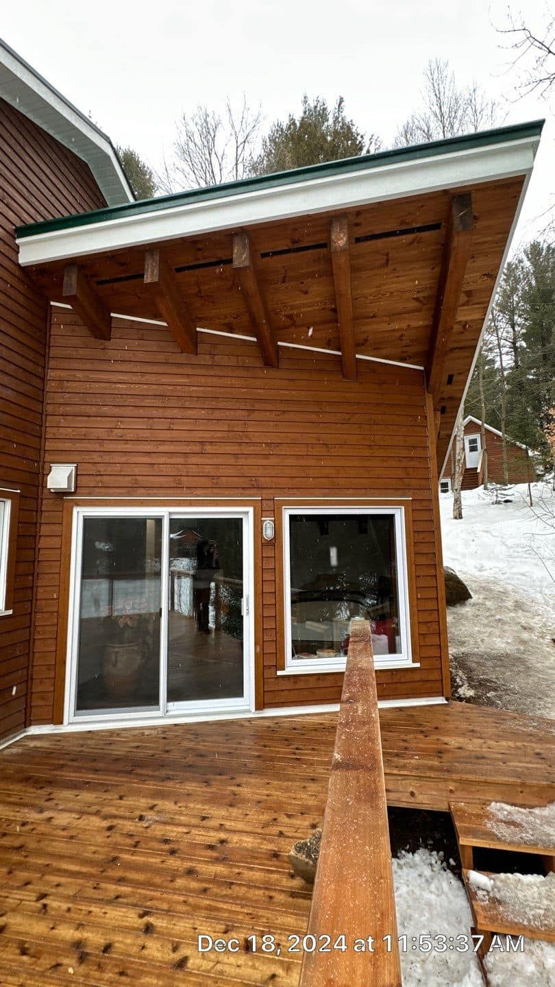 A wooden house with a sliding glass door and a wooden deck.