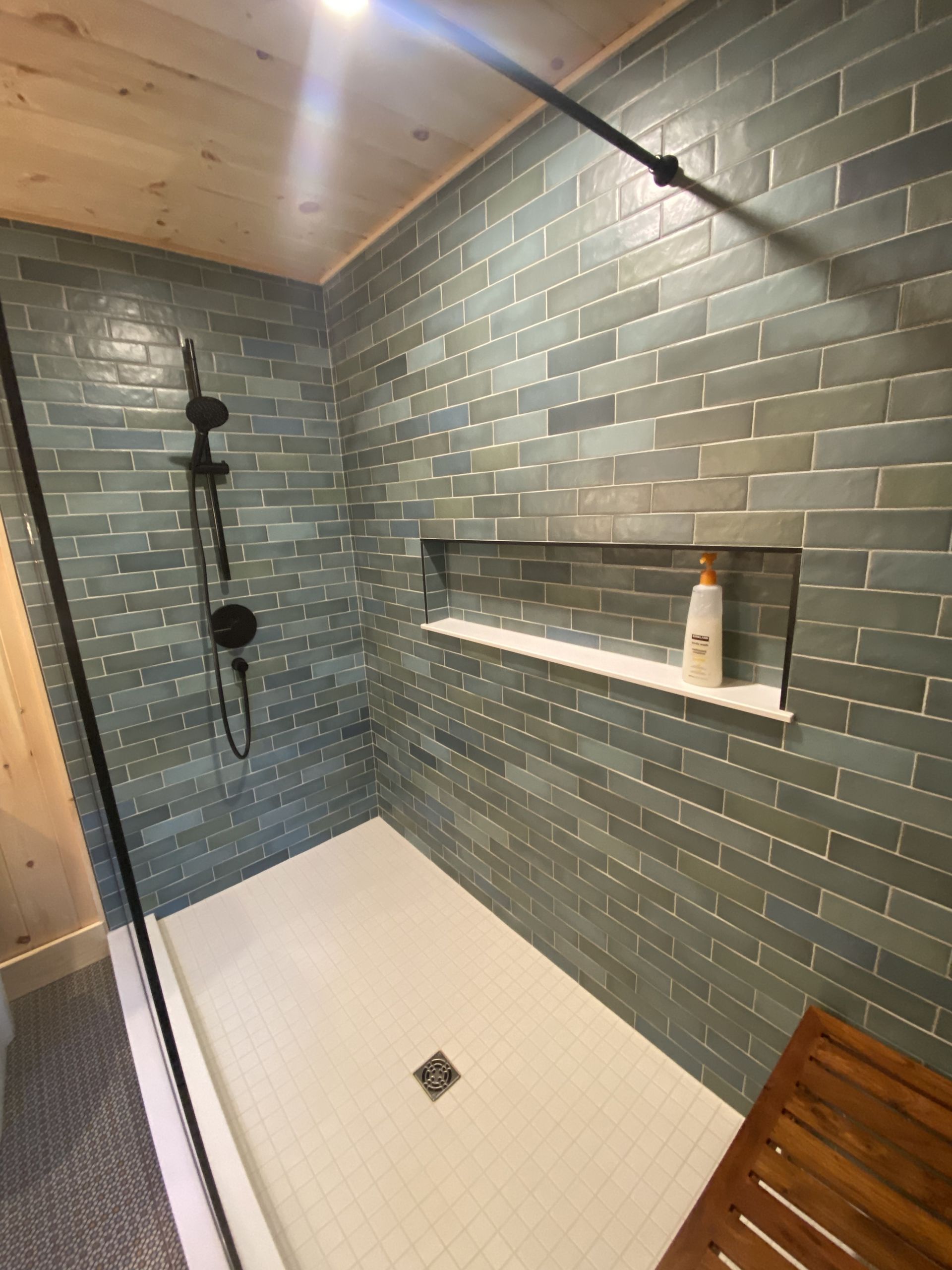 A bathroom with a walk in shower and a wooden bench.