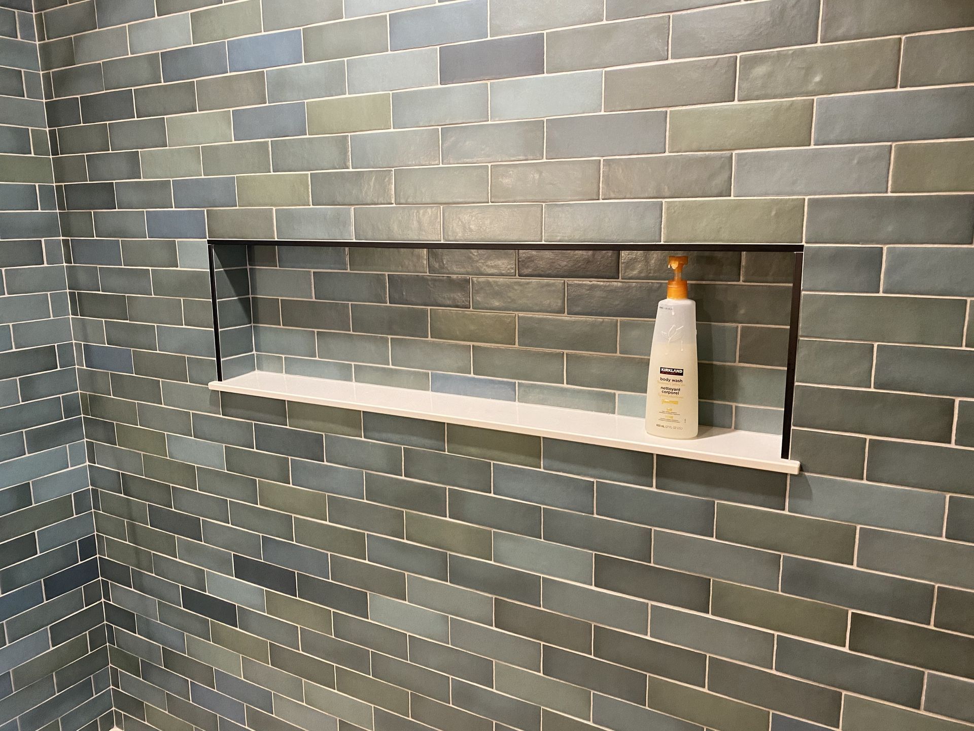 A bottle of dove shampoo sits on a shelf in a shower