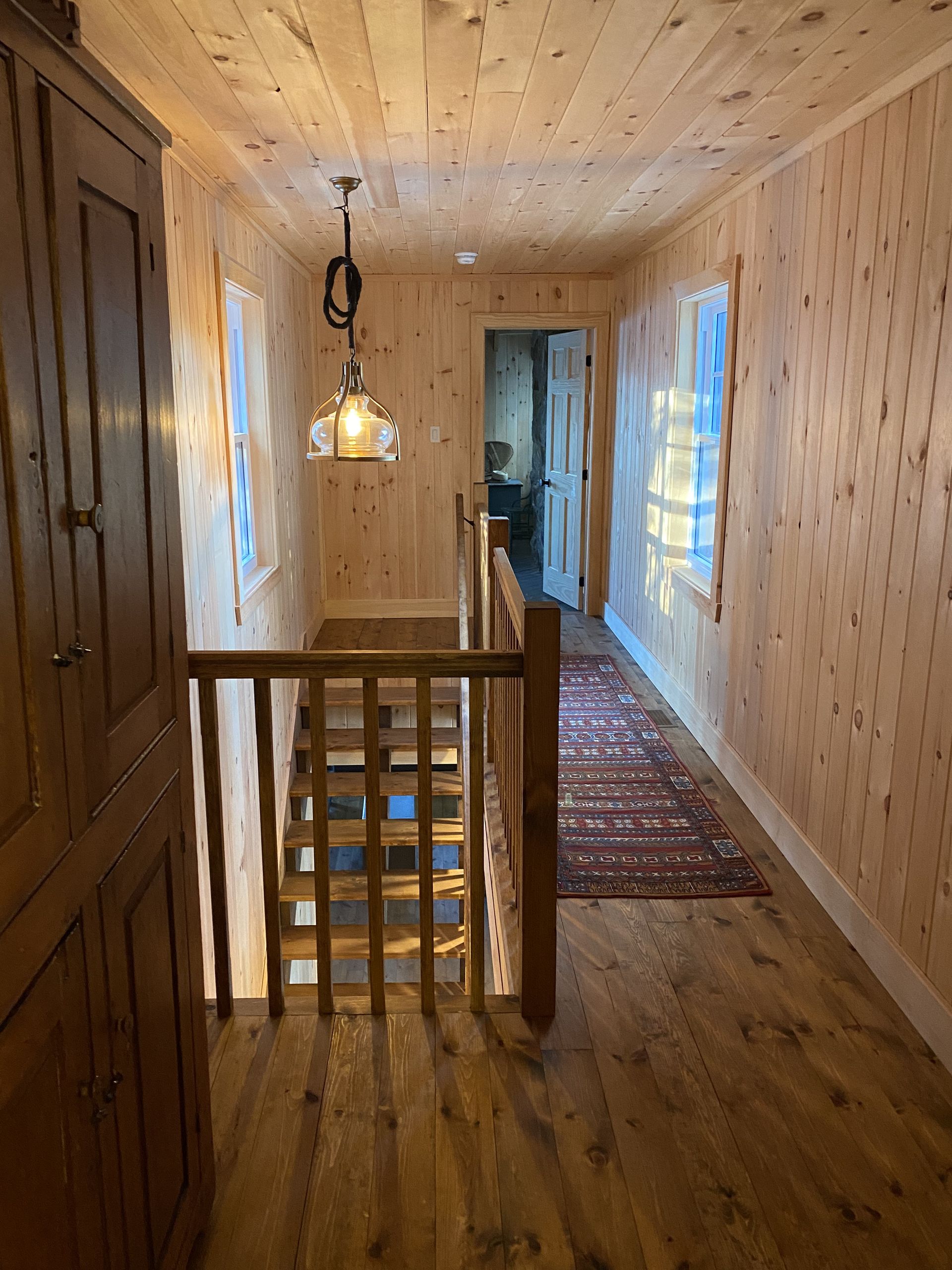 A hallway with wooden floors and stairs in a house