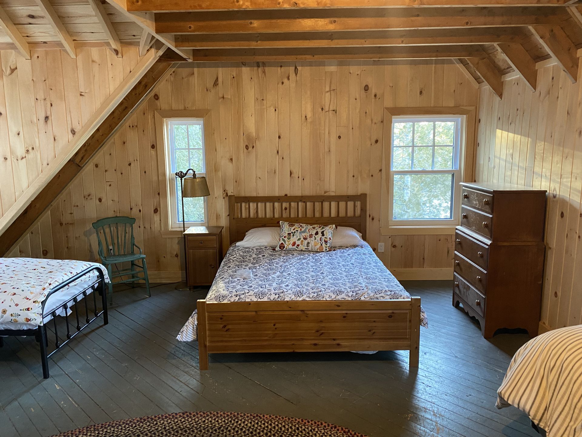 A bedroom with three beds , a dresser , and a chair.