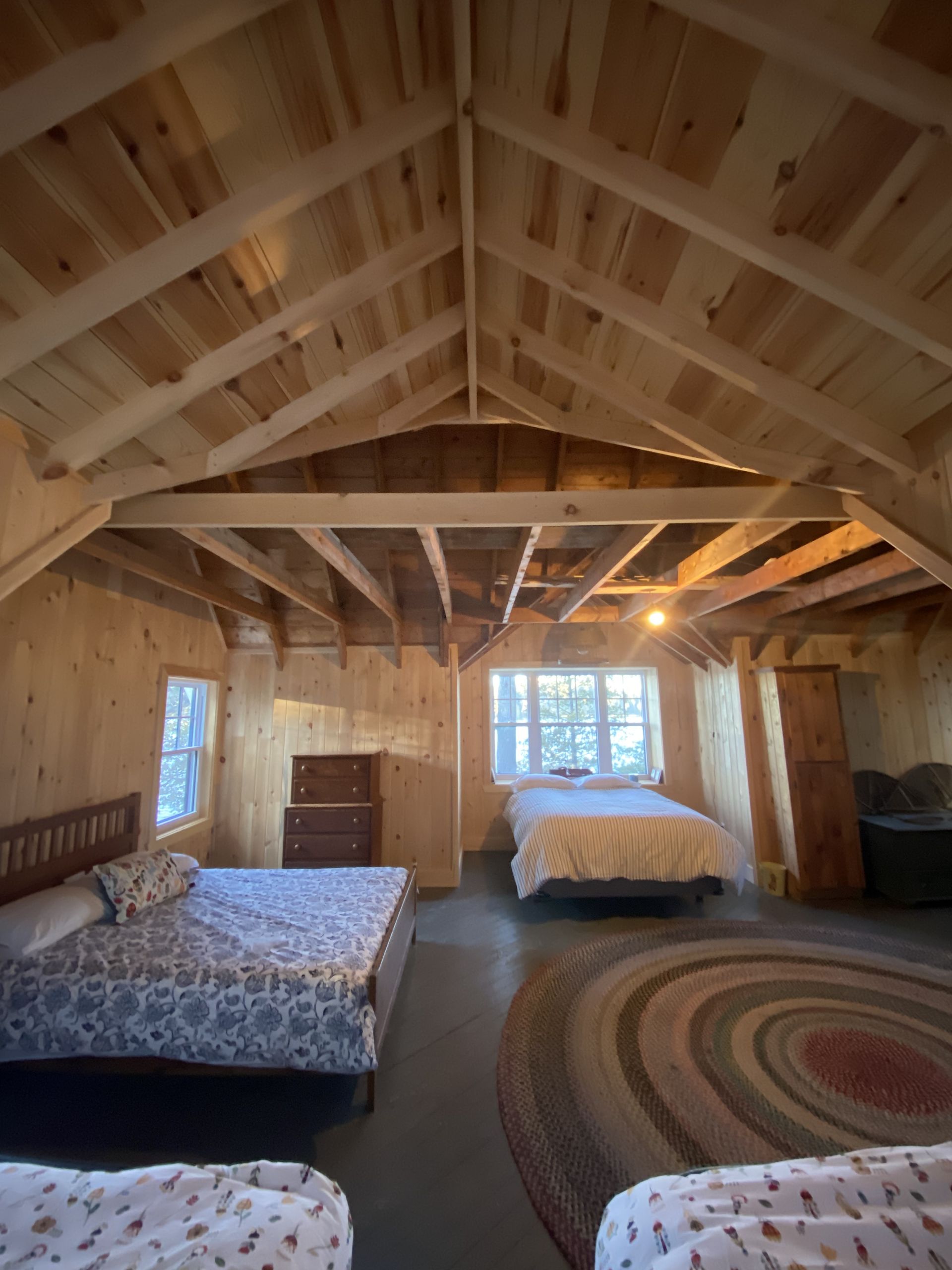 A bedroom with three beds and a rug on the floor.