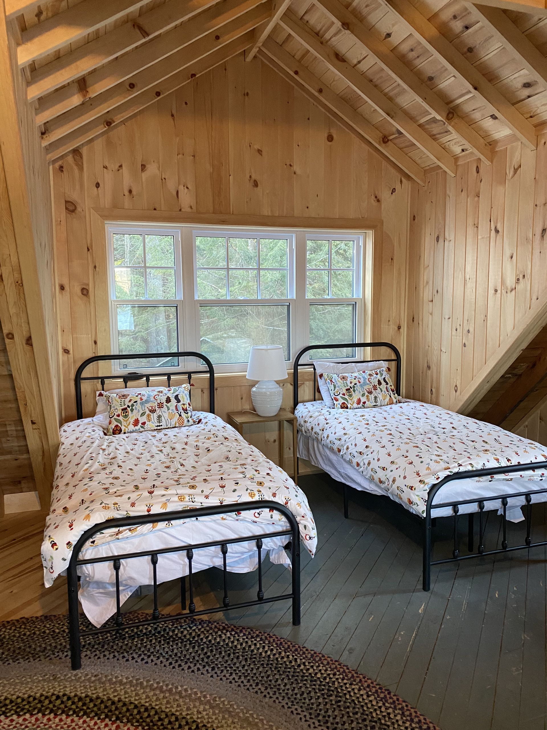 There are two beds in a room with a wooden ceiling.