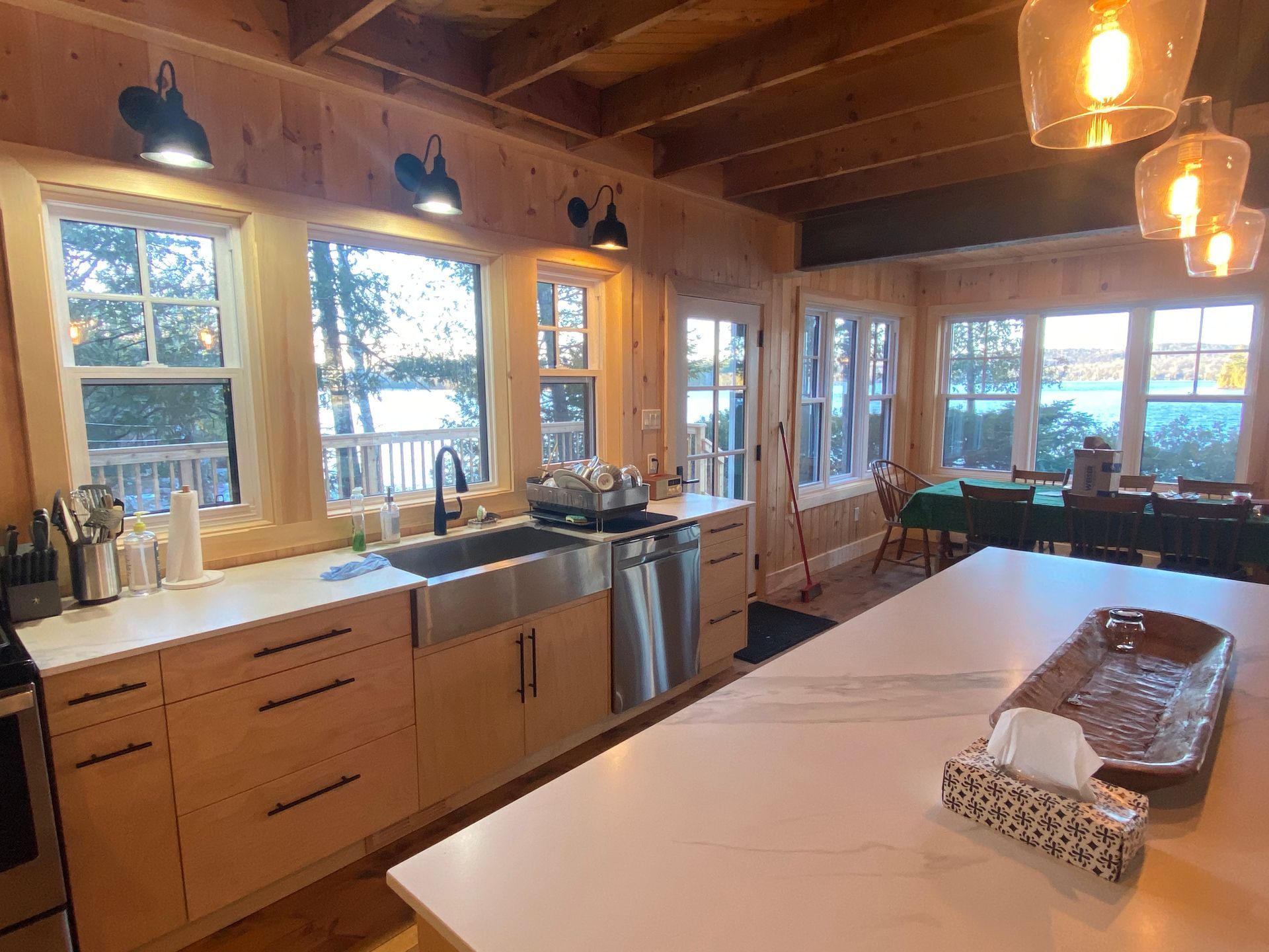 A kitchen with a large island , sink , stove , dishwasher , and lots of windows.