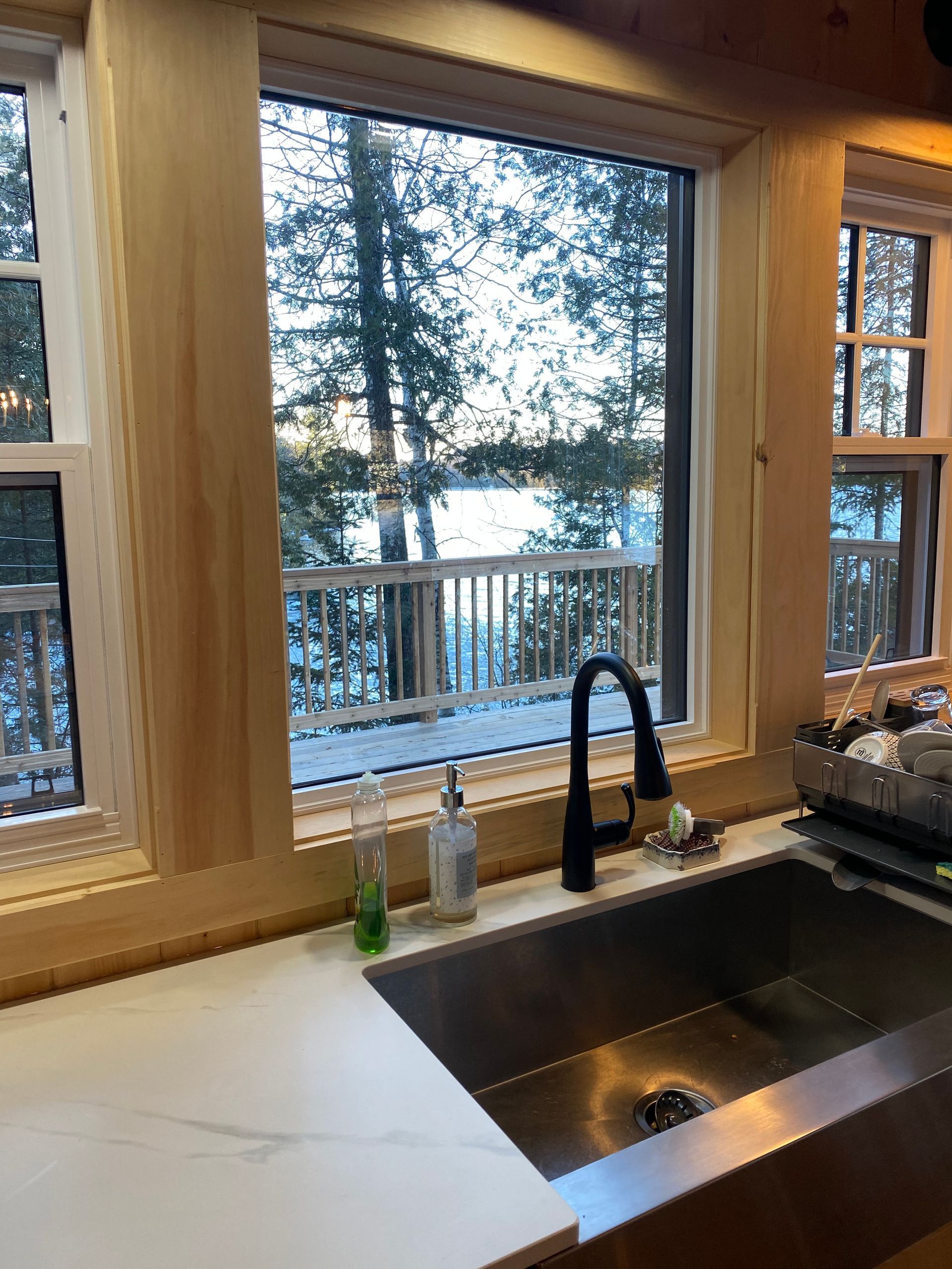 A kitchen sink with a view of a lake through a window.