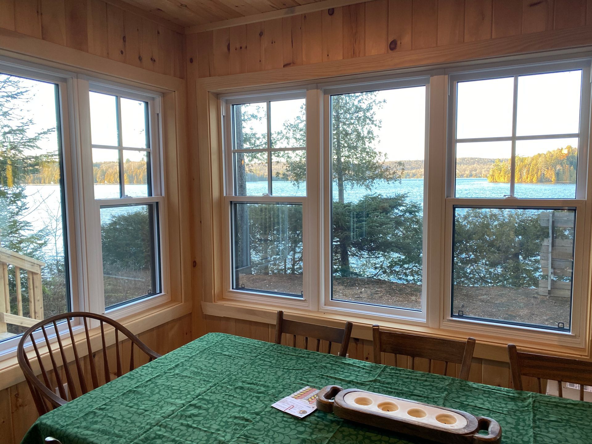 A sun room with a table and chairs and a view of a lake.